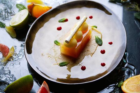 Molecular cuisine. citrus tart on a plate with fruits aroundの写真素材