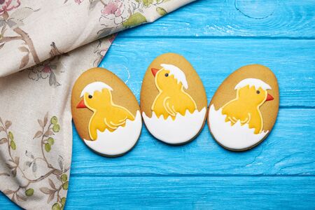 Three big Easter cookies with icing. Chicken in the egg. Napkin on a blue wooden backgroudの写真素材