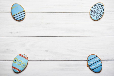 Homemade gingerbread cookies in the shape of the blue painted eggs on a wooden table. Space for text. Focus on a wood.の写真素材