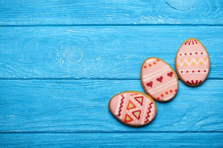 Three colorful easter cookies in egg shape on blue wooden background. With a lot of copy space.の写真素材
