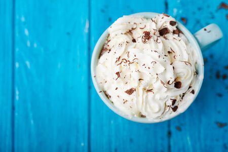 cup of coffee with cream and chocolate on blue wooden table. Close view. Top viewの写真素材