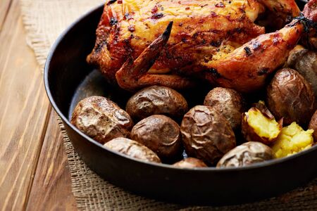 Close view at whole roasted chicken with potatoes on a wooden rustic background.の写真素材