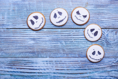 Top view at a lot of funny ghosts faces at ginger cookies for Halloween on the table at rustic...