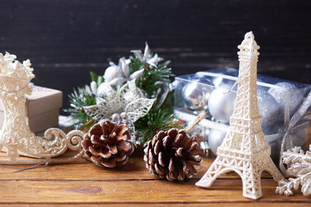 Holidays background. Toys and present on a dark wooden background. Eiffel tower, pine cones, presents and other Christmas toys on a brown wooden background.の写真素材