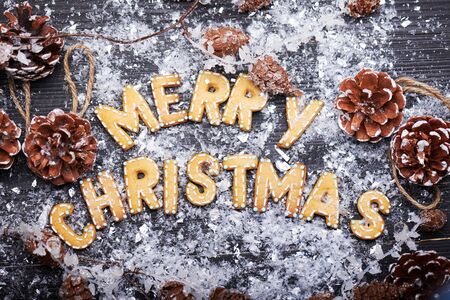 Christmas card. Christmas sign with ginger cookies on a wooden background with artificial snow. Christmas treat decorating. Top view.の写真素材