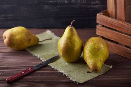 Fresh green pears and knife on a rustic background with napkin and old boxes.の写真素材