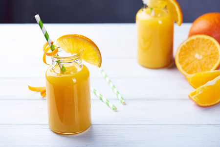 Fresh orange juice in the jar with straw on white wood table.の写真素材