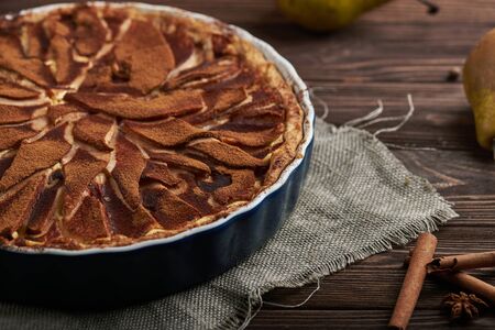 Fresh pear pie decorated with cinnamon and spices on a rustic wooden backgroundの写真素材
