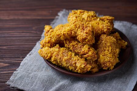 Crispy fried chicken breast on an old rustic wooden background with a sackcloth napkin, Close-up. With a lot of copy space.の写真素材