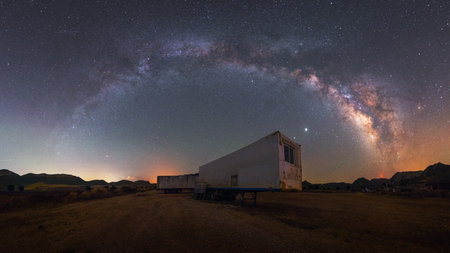night panorama of the arch of the milky way over the trailer of an abandoned truck in the desertの写真素材