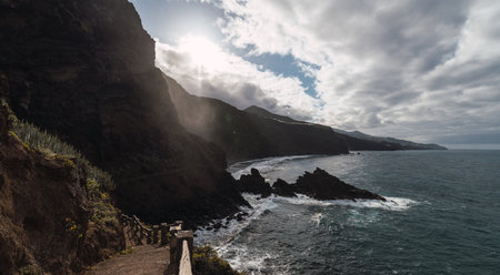 stairs with wooden railing on a cliff leading down to a black sand beachの写真素材
