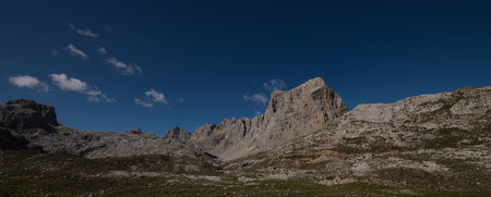 panorama of gray mountain peaks and vegetation on the ground with blue skyの写真素材