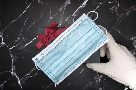 protective mask gift with hand holding on dark marble backgroundの写真素材