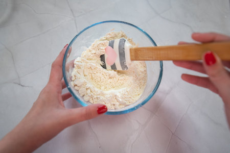 woman mixing flour in a glass bowl on white backgroundの写真素材