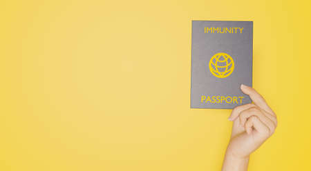immunity passport banner held by a hand on yellow background. 3d renderingの写真素材