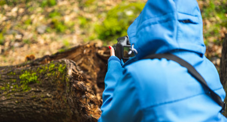 girl with blue jacket taking pictures with reflex camera in nature while raining.