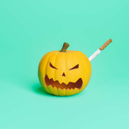 halloween pumpkin with a knife stuck in it to carve its face. halloween concept and crafts. 3d renderingの写真素材