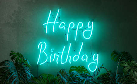 Happy birthday neon sign with plants in front of it. 3d renderingの写真素材