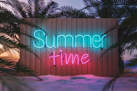 3D rendering of Summer Time bright neon signboard on wooden fence placed on sandy beach with lush palm trees under cloudless sunset skyの写真素材