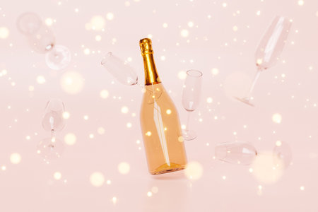3D rendering of bottle of champagne with crystal flutes levitating against pink background with sparkling lightsの写真素材
