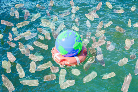 planet earth on a lifebuoy floating in the ocean polluted with plastic bottles. concept of climate change, pollution and recycling. 3d renderingの写真素材