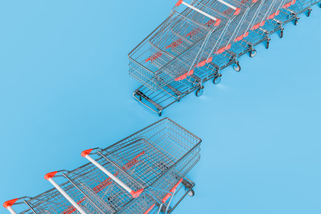 3d rendering of a diagonal line of empty metal shopping carts with red and white handles in an isometric view on a bright blue background with copy space.の写真素材