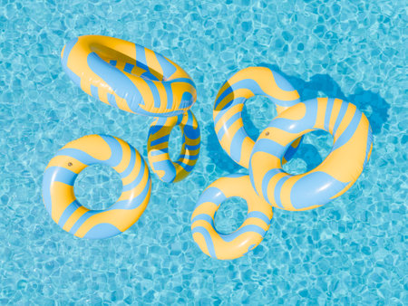 3D rendering of blue and yellow striped swim rings flying on the vibrant blue water of a sunlit swimming pool. Pool fun and summer vibes concept.の写真素材