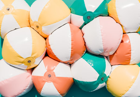 3D rendering of a playful and colorful pile of inflated beach balls with stripes on a vibrant teal backdrop. Summer background.の写真素材