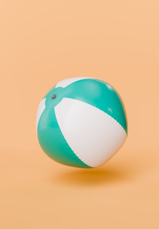 Classic white and turquoise beach ball with a visible inflation valve, floating against a peach-colored backdrop. Concept of leisure and summertime fun. 3d renderingの写真素材