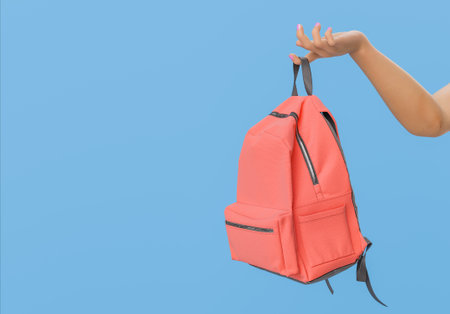 Hand holding a red backpack against a blue background. Back to school and education concept. 3d renderingの写真素材