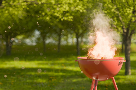 Close-up of a barbecue grill with fire and smoke in a sunny park, surrounded by greenery with copy space. Summer picnic concept. 3d renderingの写真素材