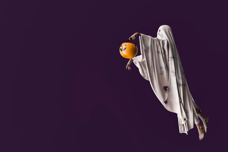 Ghost holding a plastic pumpkin bucket for trick or treating, floating on a purple background. 3d...