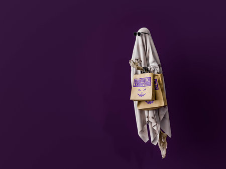 Friendly ghost carrying shopping bags on a purple background and copy space for halloween shopping and sales. 3d renderingの写真素材