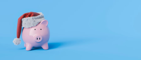 Festive piggy bank in a santa hat on a blue background with copy space. 3d renderingの写真素材