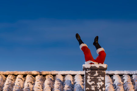 Santa Claus stuck in a chimney on a snowy roof with a view of the night sky and copy space. 3d renderingの写真素材