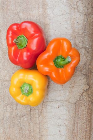 Bird's eye view of three bell peppers sitting on cutting board. 