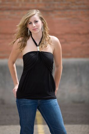 serious young blonde woman standing in front of brick wallの写真素材