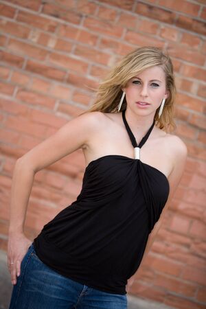 young blonde woman standing in front of brick wallの写真素材