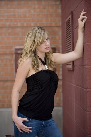beautiful young woman leaning against a wall の写真素材