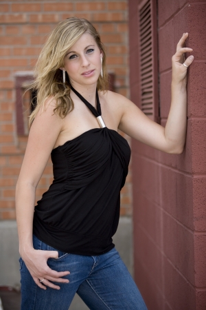 Portrait of blonde woman leaning against brick wallの写真素材