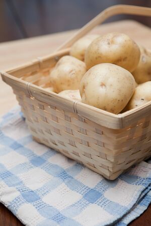 Golden potatoes in a basket on a blue and white towelの写真素材