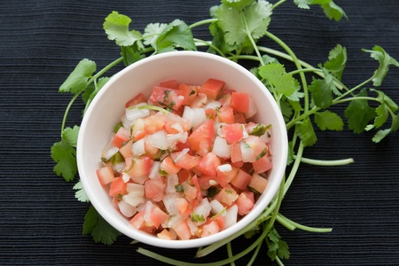bowl of pico de gallo surrounded by garnish of cilantroの写真素材