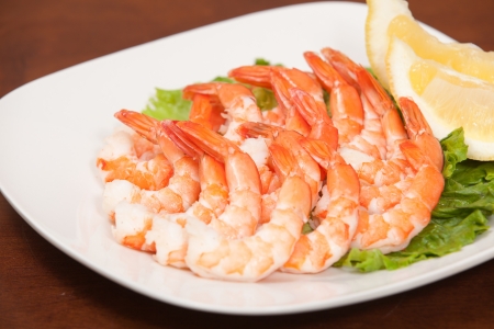 cocktail shrimp on white plate with lemon wedge garnishの写真素材