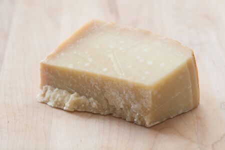 Block of Parmigiano-Reggiano imported from Italy on a wooden cutting boardの写真素材