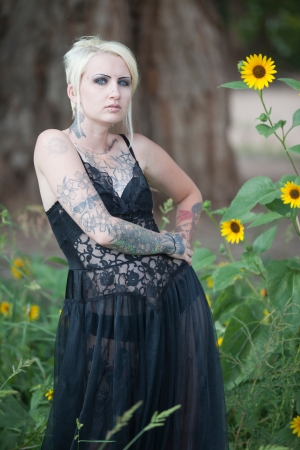 Pretty young blond haired, blue eyed goth chick wearing lingerie while outdoors in field of flowersの写真素材