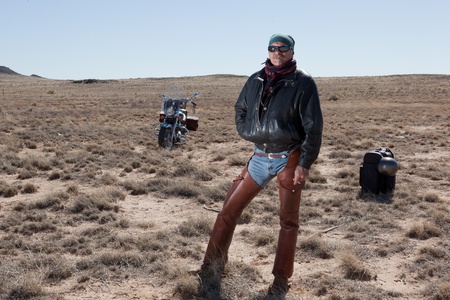 Older man wearing leather standing in front of his motorcycleの写真素材