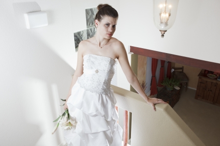 Beautiful young brunette woman with a bouquet of flowers, wearing a strapless wedding dressの写真素材