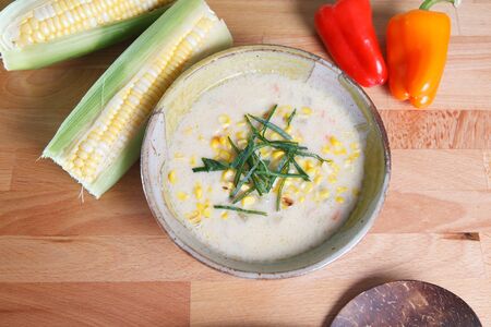 Corn Chowder soup with ears of corn and colorful bell peppersの写真素材