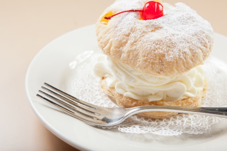 Tasty and large cream puff on a white plate with a forkの写真素材