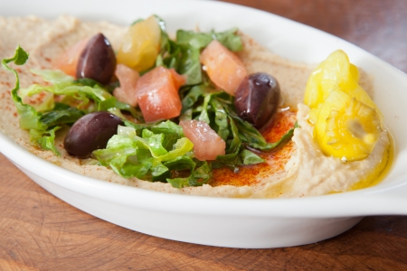 Creamy hummus topped with olive oil and a small greek saladの写真素材